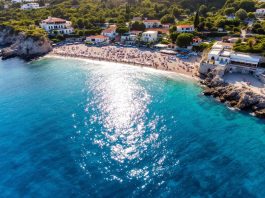 Beautiful Greek beach with clear waters and greenery.