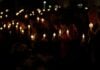 Protesters gather with candles and flowers.