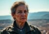 Woman veteran with medal stands against a landscape.